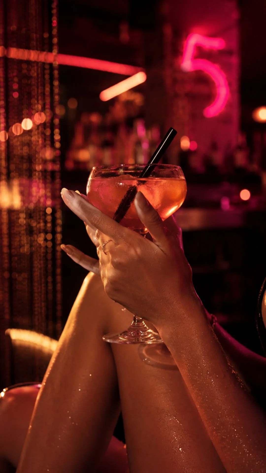 Hand hält Cocktail mit Neon-Beleuchtung