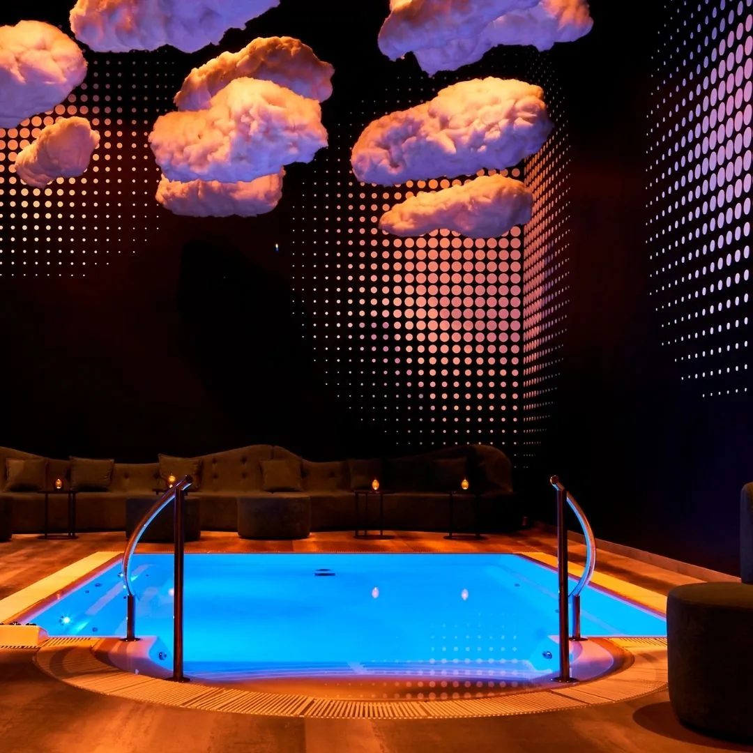 Indoor Pool mit blauem LED-Licht und Lounge-Sofas
